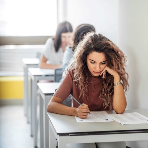 Studentin schreibt Klausur; sitzt an einem Einzeltisch